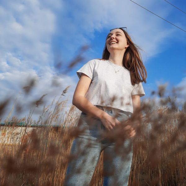 Person feeling energized and stretching outdoors with a gentle smile.